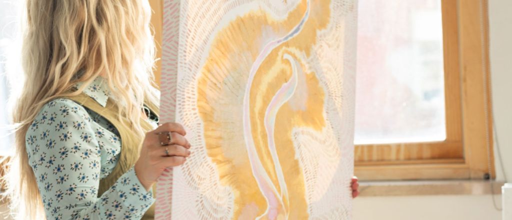 Elanni holding a gold textured painting.