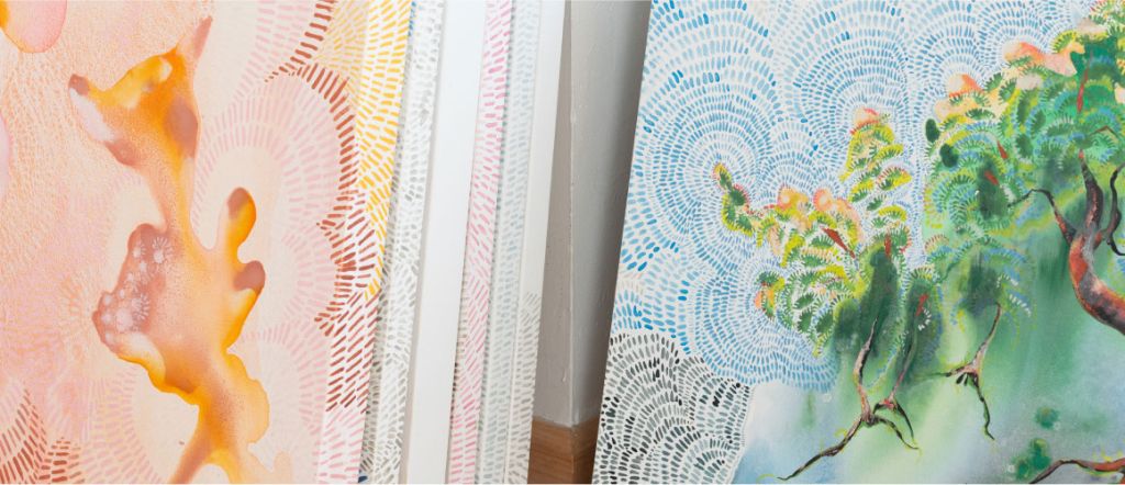 Stacks of textured painted canvases leaning against a wall.